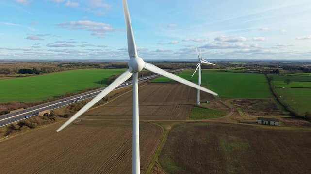 Aerial view of the M1 wind farm, with its towering turbines contrasting against the green fields and blue sky, Wootton Road, M1 wind farm, United Kingdom.