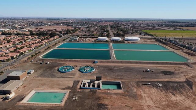 Aerial view of vibrant turquoise water treatment plant contrasting with the arid landscape, a stark reminder of resource management, El Centro, California, United States.