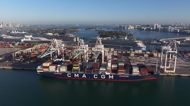 Miami, United States - 17 February 2026: Aerial view of a CMA CGM container ship docked at the Port Miami terminal, with cargo cranes and colorful containers.