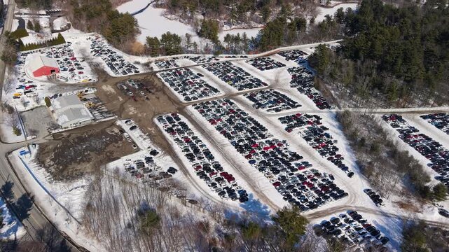 Aerial view of rows of cars parked in a vast lot, amidst snow-covered ground and bare trees, creating a stark contrast, Bellingham, Massachusetts, United States.