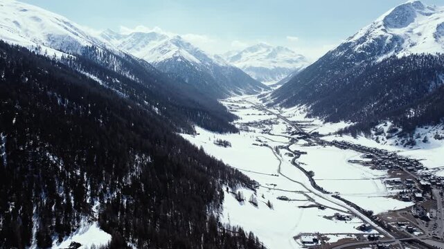Aerial view of snow-covered Livigno nestled between towering mountains, its buildings and roads etched against the pristine white landscape, Livigno, Lombardy, Italy.
