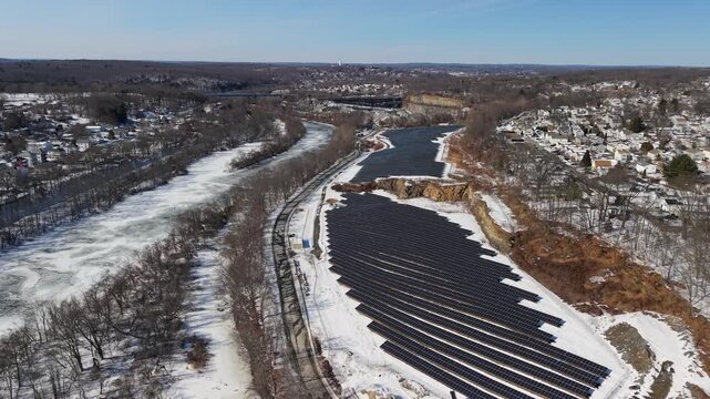 Aerial view of Blackstone River and solar panels blanketed in snow, a stark contrast against the winter landscape, Cumberland, Rhode Island, United States.