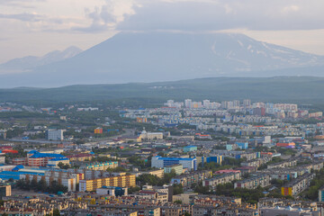 Morning cityscape. Top view of the buildings and streets of the city. Residential urban areas at sunrise. Koryaksky volcano in the distance. Petropavlovsk-Kamchatsky, Kamchatka Krai, Russian Far East.