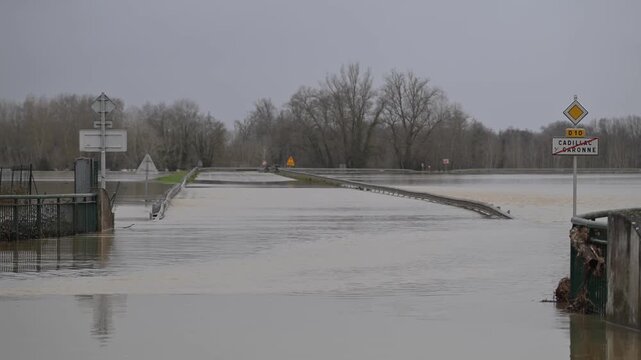 Aerial view of floodwaters engulfing a road and signs, with trees in the background, Cadillac-sur-Garonne, Nouvelle-Aquitaine, France.