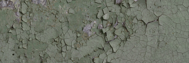 Peeling paint on the wall. Panorama of a concrete wall with old cracked flaking paint. Weathered rough painted surface with patterns of cracks and peeling. Wide panoramic texture for grunge background