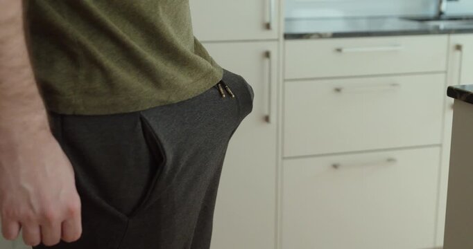 Close-up of a man standing indoors with a visible bulge under sweatpants, representing natural male arousal, intimacy themes, and human sexuality in a private setting.