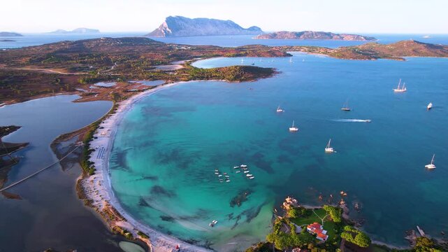 Italy Sardinia Lu Impostu beach yachts sunset 4K. Luxury boats on anchor drone. Panoramic view of round bay. Mediterranean golden hour travel. San Teodoro coast