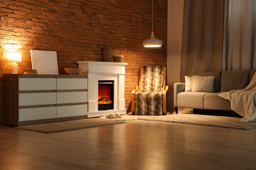Naklejka premium Cozy interior of living room with fireplace and glowing lamps in evening