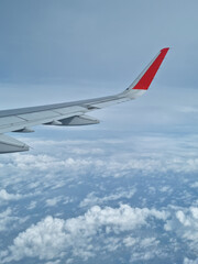 Obraz premium Airplane wing through the clouds in the sky.
