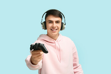 Handsome young man with headphones and game pad on background © Pixel-Shot