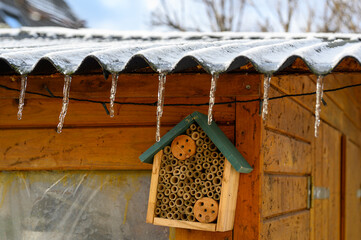 View to an insect hotel made of different materials to offer a retreat for many species. The text above is German for insect hotel.