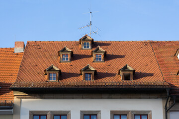 Fototapeta premium Historisches Dach mit Gauben und roten Ziegeln an einem Altbau unter blauem Himmel. (Weimar)