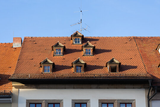 Historisches Dach mit Gauben und roten Ziegeln an einem Altbau unter blauem Himmel. (Weimar)