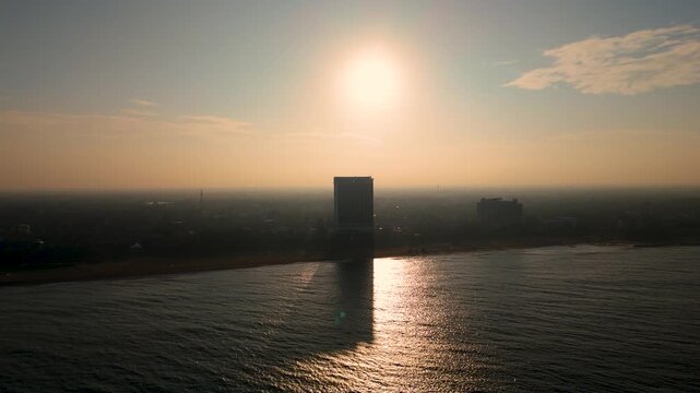 4K aerial morning sunrise over a coastal city with golden light reflecting on the ocean waves