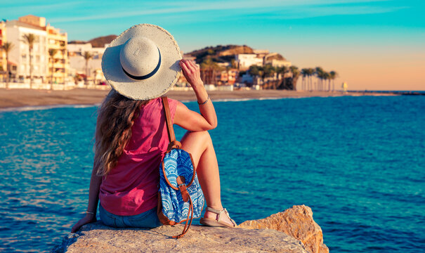 Holidays on coast of Spain. happy woman with hat and casual attire enjoying beach and city of Torrenueva , Malaga and Granada province