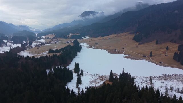 Cinematic drone footage of snowy Geroldsee (Wagenbruchsee) in winter. Located in Kruen, Bavaria. This pristine alpine lake is a famous landmark for European mountain tourism.