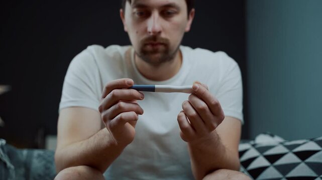 Devastated male sitting on a couch, hiding his face after seeing the test result. A dramatic representation of a life crisis and sudden psychological trauma. Emotional vulnerability and stress. 