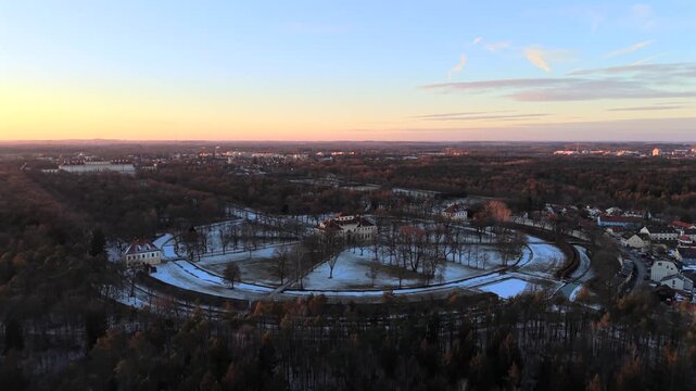 Aerial video of Palace Complex in Oberschleissheim near Munich, Bavaria, Germany. Winter sunset illuminates baroque palaces, symmetrical gardens, frozen canals in orange evening light