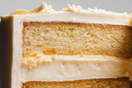 Close-up of layered cake slice, thick creamy frosting between layers, sponge moist and porous, glossy wet texture. Extra close up
