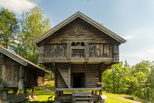 View of an old wooden building with intricate carvings stands proudly against a backdrop of lush green trees, a timeless scene, Heddal, Telemark, Norway.