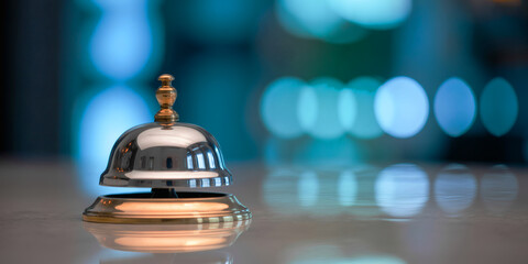 Silver Service Bell with Gold Detail on Reflective Surface and Blue Bokeh Background &ndash; Hotel Reception Concept