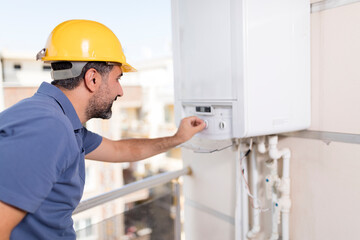 Professional handyman and electrician in blue overalls and yellow safety helmet performing home...