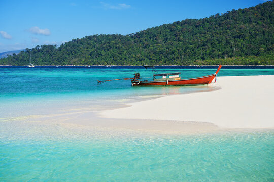 Boat on tropical sea coast with white sandy beach and turquoise water