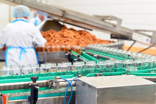 Production of sausages on a conveyor belt in a large meat processing plant - Industrial food processing - Workers in work clothes