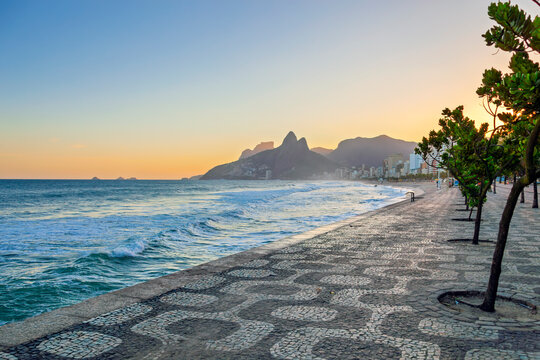 Scenic sunset view of Ipanema Beach boardwalk and Morro Dois Irm&atilde;os mountains in Rio de Janeiro, Brazil.