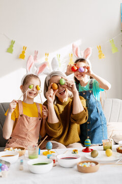 Grandparent and grandchildren celebrating Easter, having fun with colorful dyed eggs