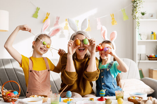 Grandmother and granddaughters having Easter fun covering eyes with colored eggs