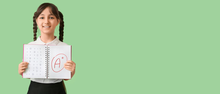 Happy girl holding notebook with good results of school test on green background with space for text