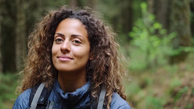 Mindfulness wellness and nature connection concept. Happy young woman with curly hair closed eyes breathing fresh air while hiking in a green summer forest.
