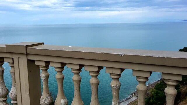 An ancient stone parapet overlooking the sea and clouds