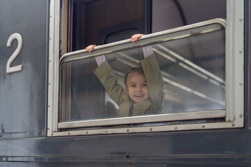 View through the window of happy girl traveling by old tourist train