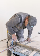 Construction worker hand cutting ceramic tile with manual tile cutter, hand closeup