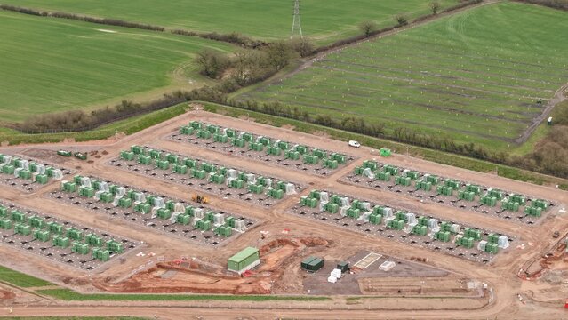 Aerial view of a new Battery Energy Storage Systems BESS construction site with rows of green units contrasting with the brown earth, National Grid Hams Hall Substation, Birmingham, United Kingdom.