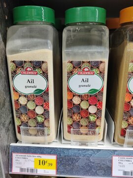 Saujon, France - January 24, 2026: Intermarche. Granulated garlic spice in transparent containers with colorful labels on a supermarket shelf, visible price tag and brand name Columbia