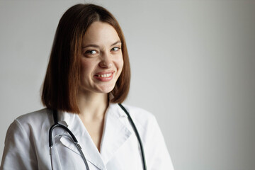 Positive female doctor in a white coat with a stethoscope on her neck in a hospital, portrait of a doctor.