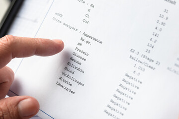 Doctor reviewing urine analysis laboratory report during medical examination