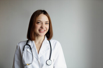 Positive female doctor in a white coat with a stethoscope on her neck in a hospital, portrait of a doctor.