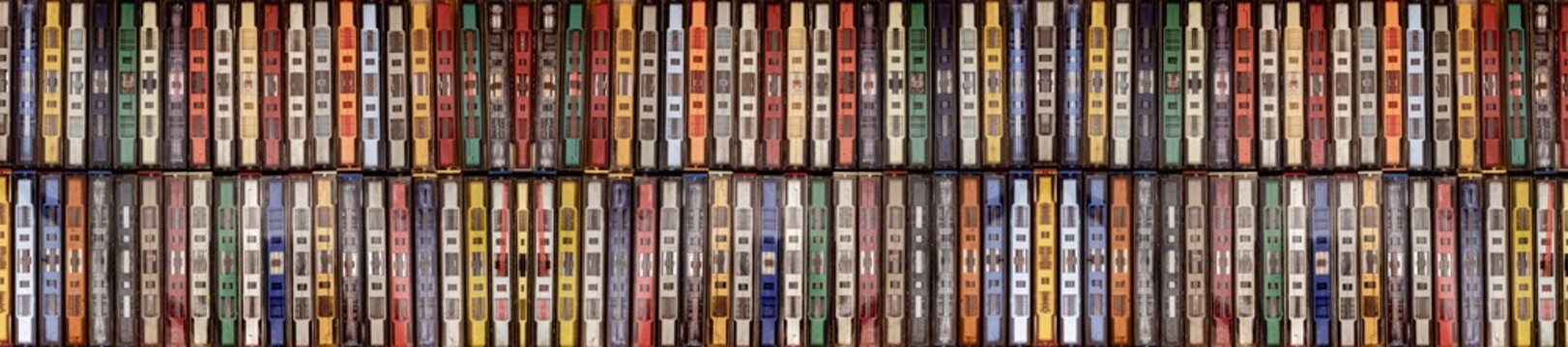 a collection of vintage cassette tapes lined up neatly, showcasing a variety of colored plastic cases