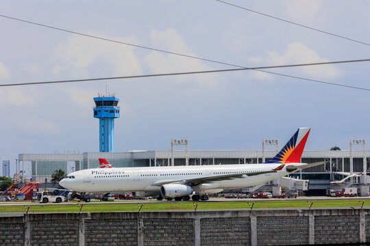 Manila, Philippines - 2025 July 13: A Philippine Airlines Airbus A330 aircraft taxis on the taxiway at Ninoy Aquino International Airport under a clear sky. A light blue control tower 