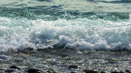 Sea waves and a pebble beach on a sunny summer day. Selective focus.