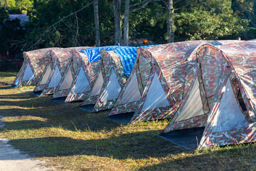 Canvas tents and traditional teepees pitched amidst the green grass in the forest during the summer. © wannasak