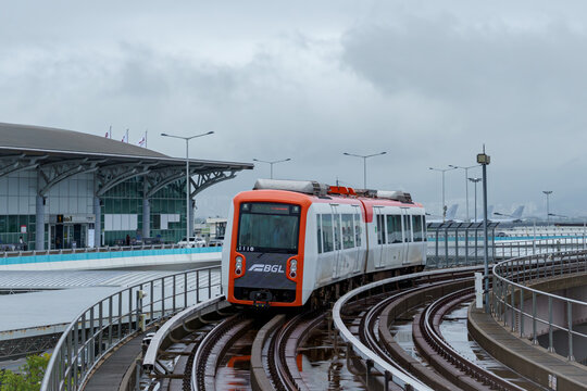 Busan, South Korea - 2024 June 22: A driverless train of the Busan-Gimhae Light Rail Transit (BGL) runs on an elevated track near Gimhae International Airport under a cloudy sky.