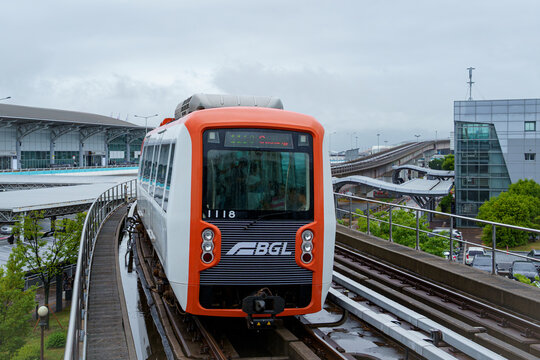 Busan, South Korea - 2024 June 22: A driverless train of the Busan-Gimhae Light Rail Transit (BGL) runs on an elevated track near Gimhae International Airport under a cloudy sky.