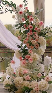 wedding arch of white rose flowers on the river bank before the wedding ceremony of the bride and groom, festive romantic decor