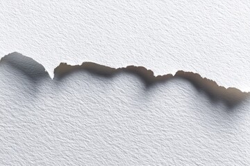 Close-up of textured white paper with a torn edge casting a shadow