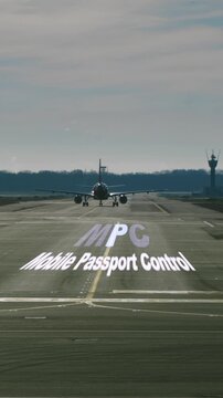 Airplane approaching on an airport runway with animated Mobile Passport Control text, a concept for expediting entry into the United States for pre approved travelers and border security